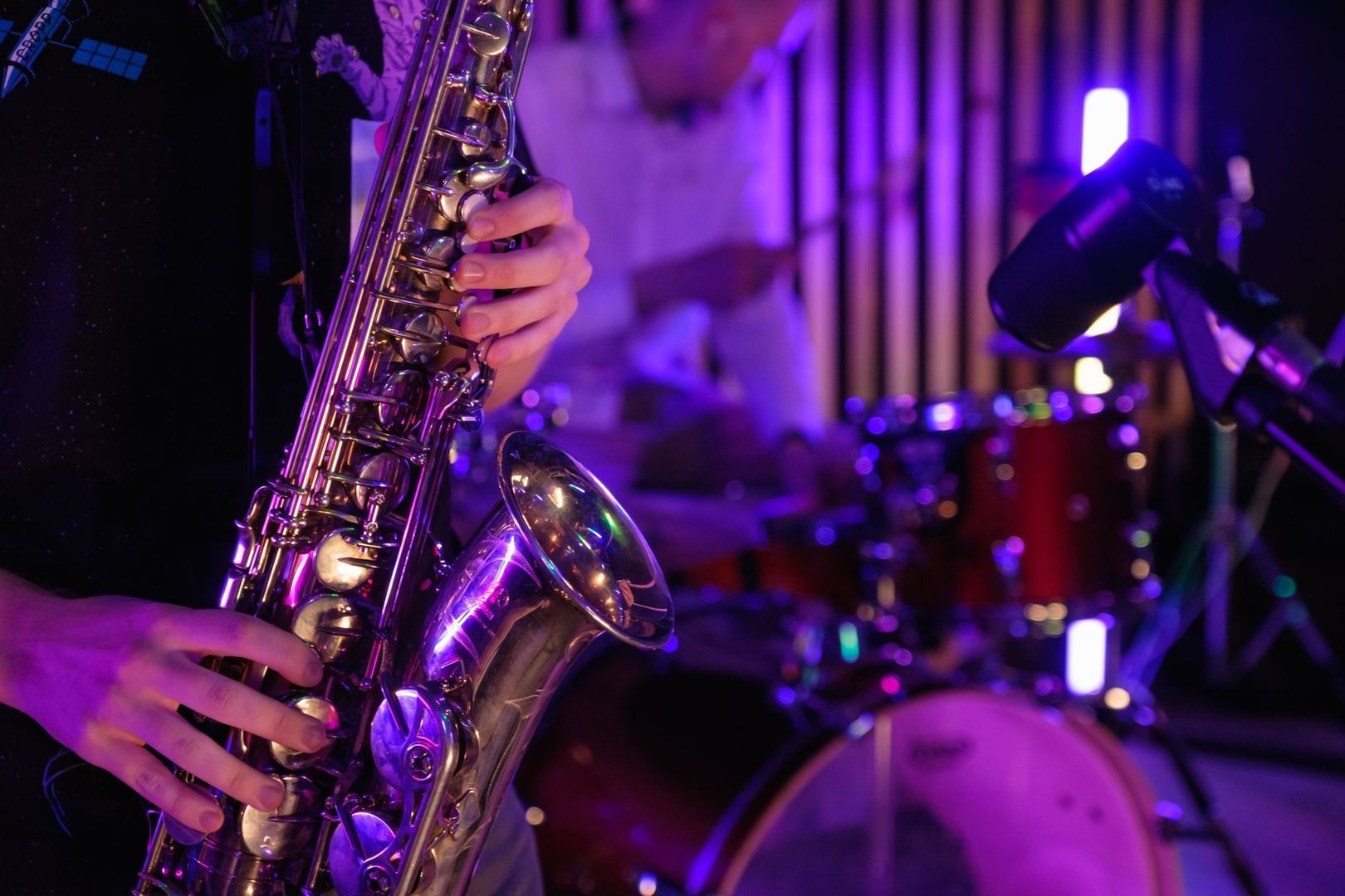Närbild av saxofonist och mikrofon under en lila jazzspelning