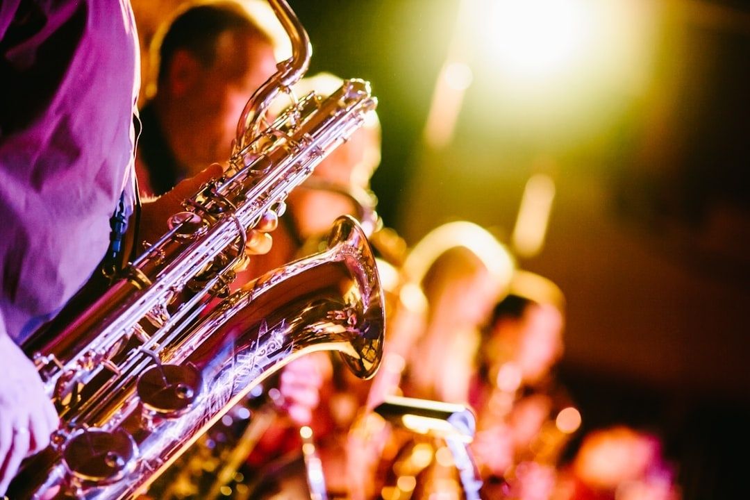 Närbild av saxofonist som spelar på en färgstarkt belyst scen